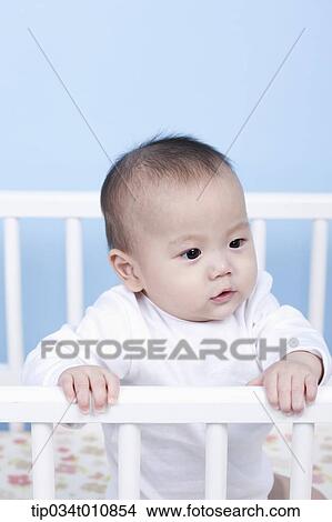Picture - a baby inside a crib. Fotosearch