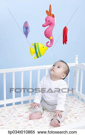 Stock Photography - a baby inside a crib playing with mobile. Fotosearch