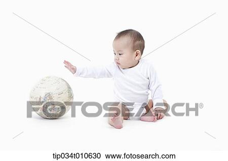 Stock Image - a baby playing with a globe. Fotosearch