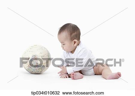 Stock Image - a baby playing with a globe. Fotosearch