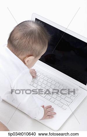Stock Image - a baby playing with a laptop . Fotosearch
