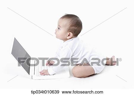 Stock Photo - a baby playing with a laptop . Fotosearch