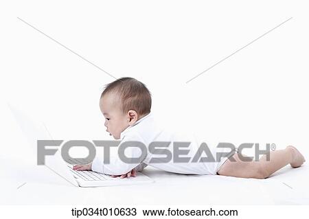 a baby playing with a laptop while lying on the floor View Large Photo Image Stock Image - a baby playing with a laptop while lying on the floor. Fotosearch