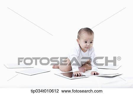 Stock Image - a baby playing with several tablet PCs. Fotosearch