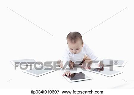 Stock Photo - a baby playing with several tablet PCs. Fotosearch
