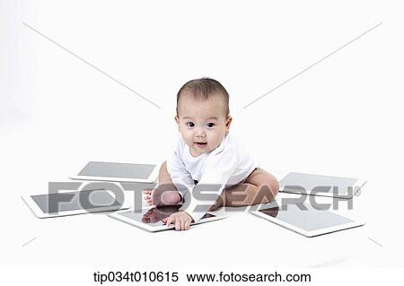 Stock Photography - a baby playing with several tablet PCs. Fotosearch