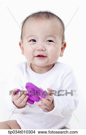 Picture - a baby smiling while playing with alphabet block. Fotosearch