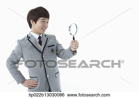 Stock Photograph - a boy in a school uniform holding a magnifying glass. Fotosearch