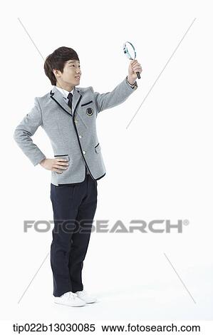 Stock Photography - a boy in a school uniform holding a magnifying glass. Fotosearch