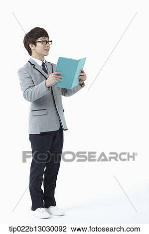Stock Image - a boy in a school uniform reading a book. Fotosearch