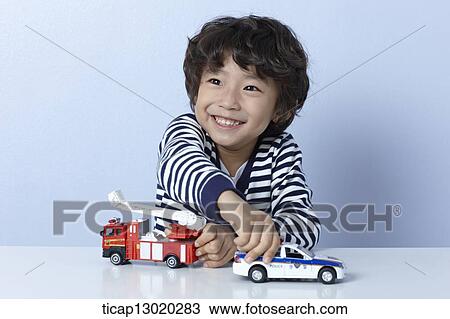 a boy playing with a fire truck and a police car View Large Photo Image Stock Image - a boy playing with a fire truck and a police car. Fotosearch