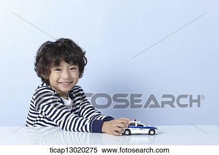 Stock Photography - a boy playing with a police car. Fotosearch