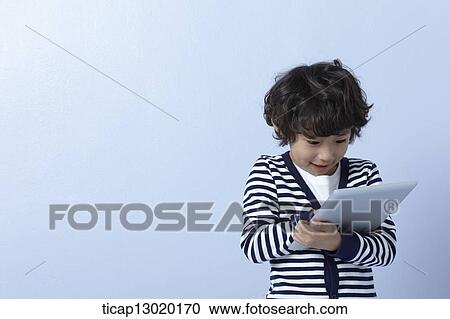 Stock Image - a boy playing with a tablet device. Fotosearch