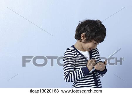 Stock Photo - a boy playing with a tablet device. Fotosearch