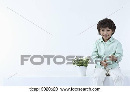 Stock Image - a boy sitting next to a plant. Fotosearch