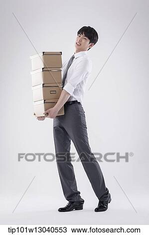 Stock Image - a business man carrying a pile of boxes. Fotosearch