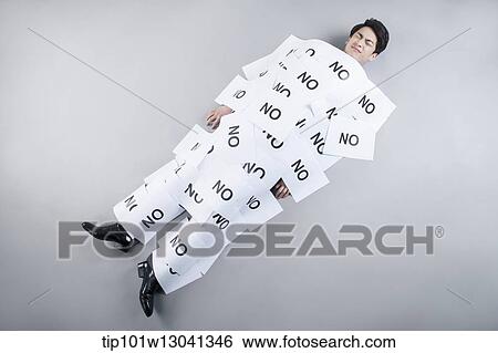 Stock Photograph - a business man covered by papers that say no. Fotosearch