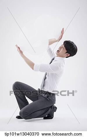 Stock Image - a business man holding a dollar sign. Fotosearch