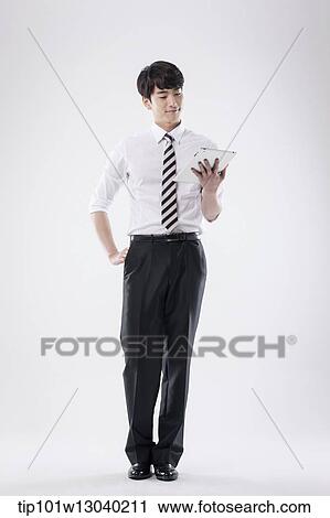 Stock Image - a business man holding a tablet. Fotosearch
