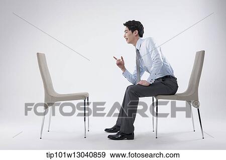 Stock Photo - a business man sitting and talking to an empty chair. Fotosearch
