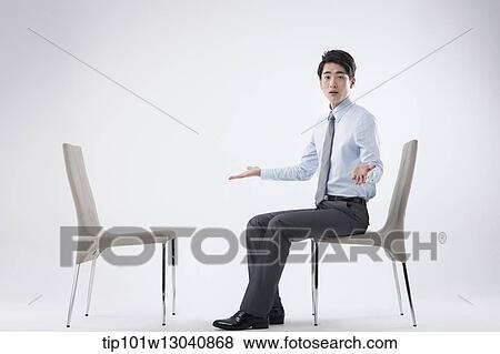 Stock Photo - a business man sitting and talking to an empty chair. Fotosearch