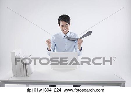 Picture - a business man sitting at a desk. Fotosearch