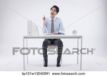 Stock Image - a business man sitting at a desk. Fotosearch