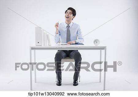 Stock Image - a business man sitting at a desk. Fotosearch