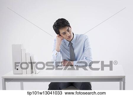 Stock Image - a business man sitting at a desk. Fotosearch