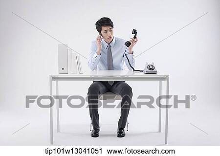Stock Image - a business man sitting at a desk. Fotosearch