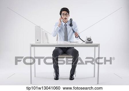 Stock Image - a business man sitting at a desk. Fotosearch