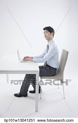 Stock Image - a business man sitting at a desk. Fotosearch