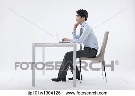 Stock Image - a business man sitting at a desk. Fotosearch