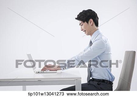 Stock Image - a business man sitting at a desk. Fotosearch