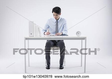 Stock Photo - a business man sitting at a desk. Fotosearch