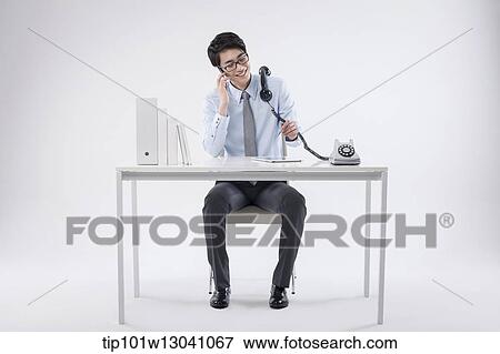 Stock Photo - a business man sitting at a desk. Fotosearch