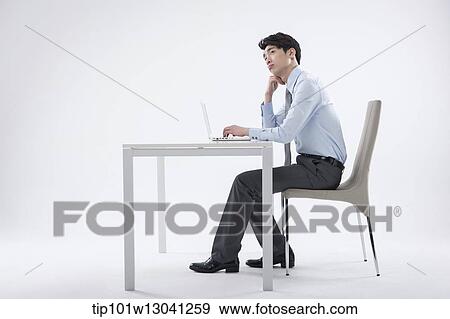 Stock Photo - a business man sitting at a desk. Fotosearch