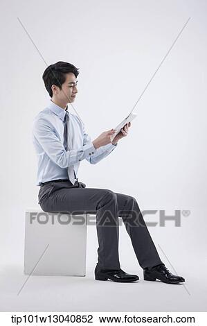 Stock Image - a business man sitting with a tablet. Fotosearch