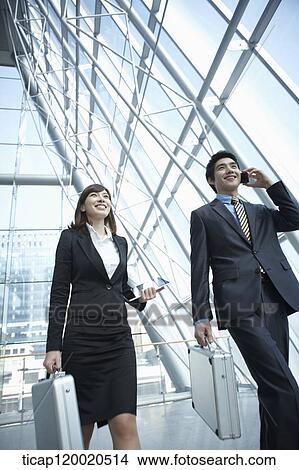 Picture - a business man walking with a business woman. Fotosearch