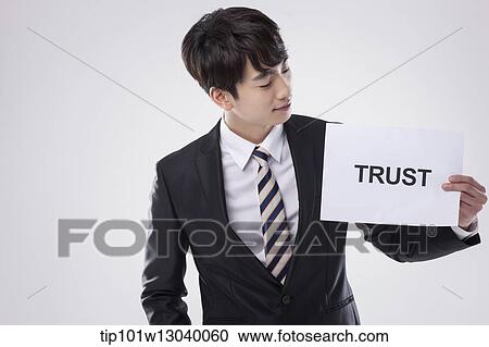 Stock Image - a business man with a paper saying trust. Fotosearch