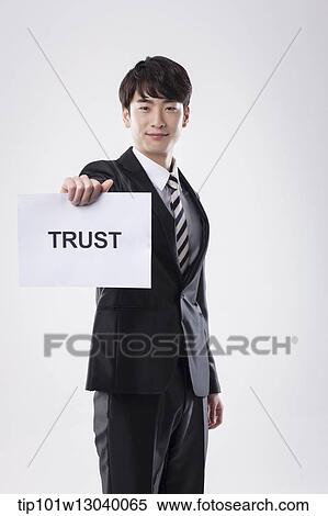 Stock Photography - a business man with a paper saying trust. Fotosearch