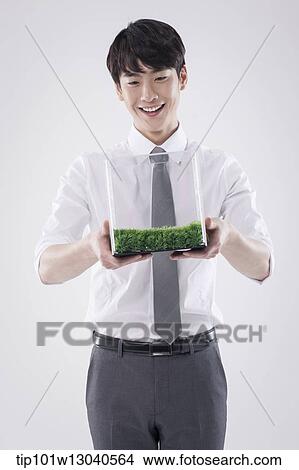 Picture - a business man with a transparent box of grass. Fotosearch