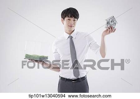 Picture - a business man with a transparent box of grass and a house of money. Fotosearch