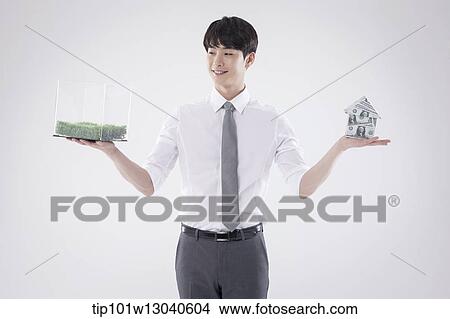 a business man with a transparent box of grass and a house of money View Large Photo Image Picture - a business man with a transparent box of grass and a house of money. Fotosearch