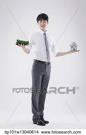 Picture - a business man with a transparent box of grass and a house of money. Fotosearch