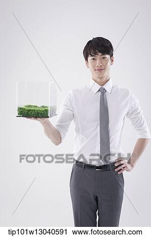 Stock Image - a business man with a transparent box of grass. Fotosearch