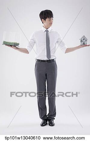 Stock Image - a business man with a transparent box of grass and a house of money. Fotosearch