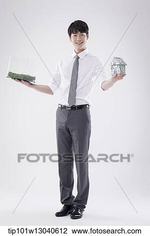 Stock Image - a business man with a transparent box of grass and a house of money. Fotosearch
