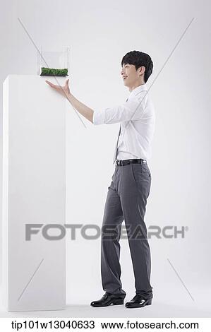 Stock Image - a business man with a transparent box of grass. Fotosearch