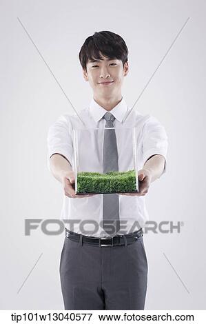 Stock Photo - a business man with a transparent box of grass. Fotosearch